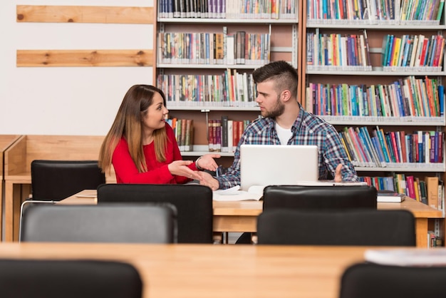 Gestresste leerlingen op de middelbare school zitten aan de bibliotheekbalie Ondiepe scherptediepte