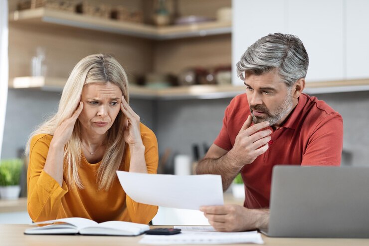 Gestresste man en vrouw zitten aan de keukentafel documenten te lezen