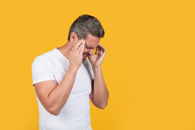 Gestresste man in shirt heeft migraine geïsoleerd op geel met kopieerruimte gestreste man met migraine