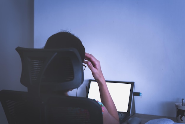 Gestresste zakenvrouw hand op haar hoofd die 's avonds laat op laptop werkt.