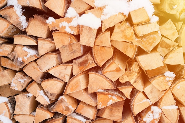 Gestructureerde brandhout achtergrond gehakt hout voor aanmaakhout houtstapel met gestapeld brandhout berkenboom bedekt verse ijzige bevroren sneeuw en sneeuwvlokken koud weer en besneeuwde winter seizoen flare