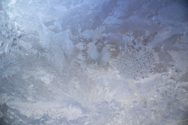 Gestructureerde vorstpatronen op het glas. IJskristallen op het raam op een koude, ijzige dag in de winter.