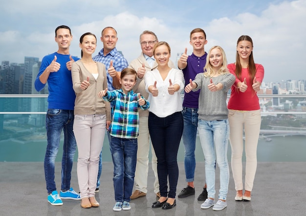 gesture, family, travel, generation and people concept - group of smiling men and women  showing thumbs up over singapore city background