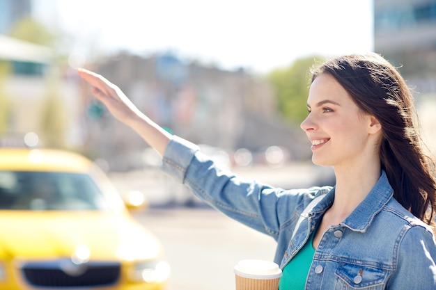 gesture, lifestyle, travel and people concept - happy young woman or teenage girl drinking coffee from paper cup on city street