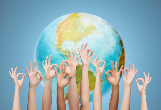 жест, люди, человечество и концепция сообщества - человеческие руки показывают знак "ок" над земным шаром и синим фоном