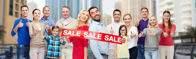 gesture, shopping and people concept - group of happy people with sale sign showing thumbs up