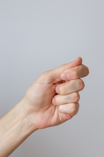 Gesture and sign, male hand holds something on a light background