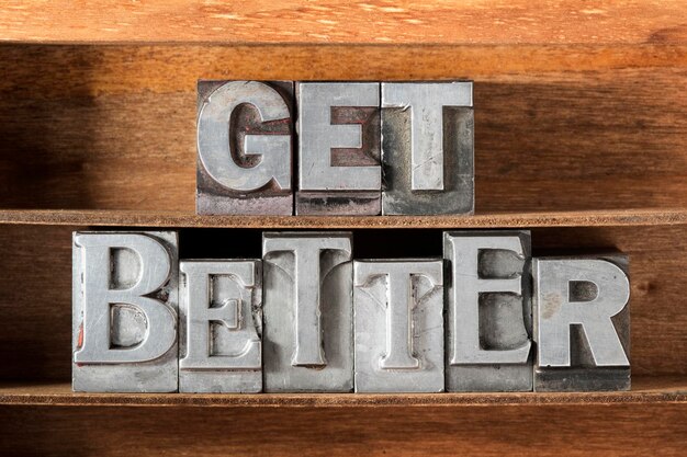 Photo get better phrase made from metallic letterpress type on wooden tray