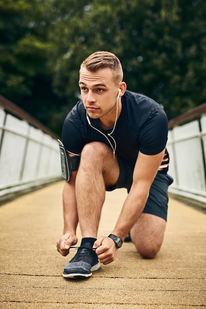 Приготовьтесь выбить сердце из колеи Снимок спортивного молодого человека, завязывающего шнурки во время тренировки на свежем воздухе