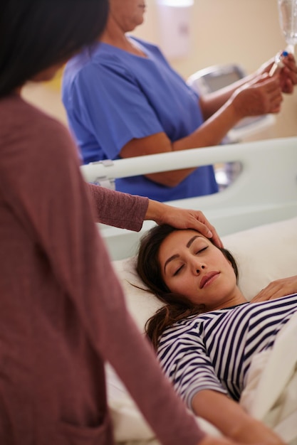 Get well soon Shot of a woman touching her friends forehead as she lays in her hospital bed