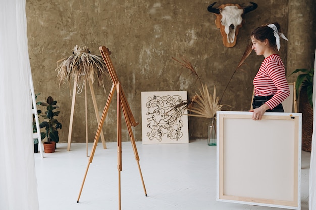 Getalenteerde jonge vrouw die in haar vrije tijd een groot canvas draagt om te schilderen