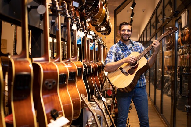 Getalenteerde kaukasische muzikant die een nieuw gitaarinstrument test in de muziekwinkel.