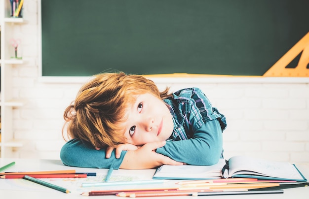 Getalenteerde kindleraren dagschoolkinderen terug naar school kind leert in de klas op de achtergrond van bla...