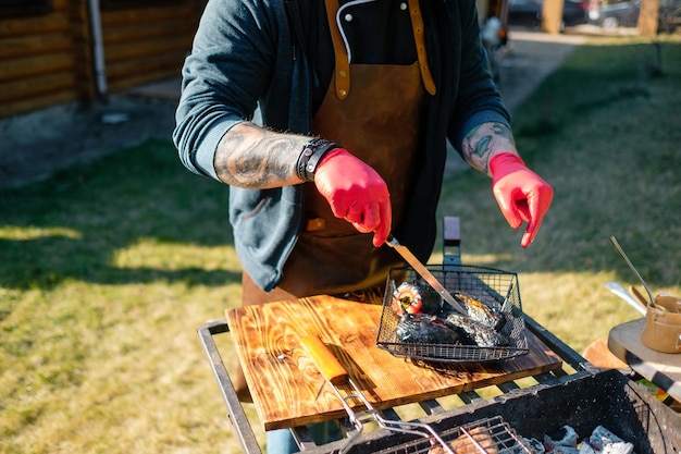 Getatoeëerde chef-kok met rubberen handschoenen groenten buitenshuis hakken Concept van grill party