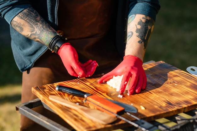 Getatoeëerde chef-kok met rubberen handschoenen uien buiten hakken