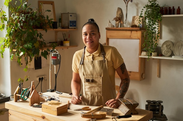 Getatoeëerde vrouwelijke artiest op werkstation in gezellige studio