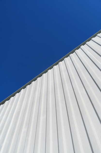 Getextureerde witmetaalstructuren diagonaal tegen een blauwe hemel. Abstractie in gebouwen