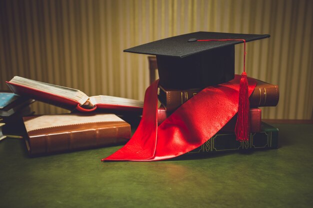 Getinte close-upfoto van rood lint en afstudeerpet op klassieke tafel