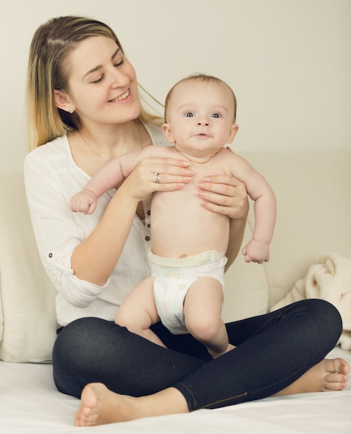 Getinte foto van een babyjongen van 6 maanden ontspannen op bed met zijn moeder