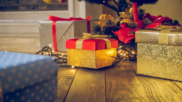 Getinte kerst achtergrond. Gouden geschenkdoos, krans en gloeiende lichten op houten vloer in woonkamer