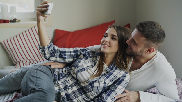 Getrouwd gelukkig stel dat 's ochtends een selfie maakt terwijl ze thuis op bed ligt