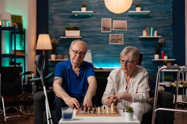 Getrouwd oud stel dat thuis schaakspel speelt op tafel