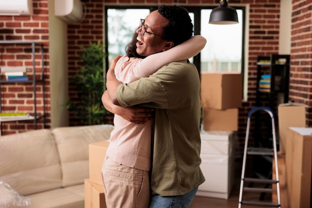 Getrouwde man en vrouw knuffelen en voelen zich gelukkig over het intrekken, het kopen van eerste huishoudelijke flat samen. Levensgebeurtenis vieren en trots zijn op verhuizing van onroerend goed, een nieuw begin.