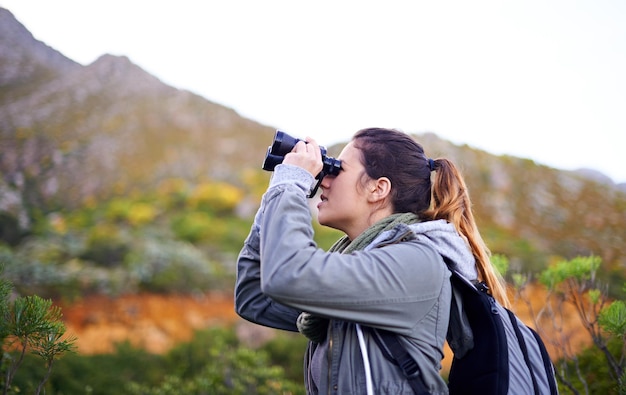 Getting a better view Shot of an attractive young woman looking through binoculars while on a hike