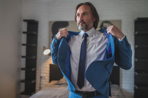 Photo getting dressed. bearded good-looking man putting on his jacket