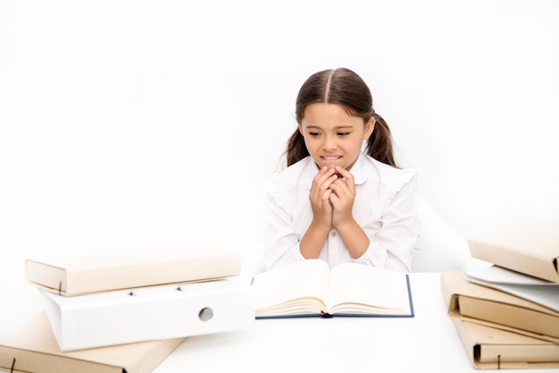 Getting education in reading Small school child have literature lesson Schoolgirl reading school book at desk Adorable pupil develop reading skills Little girl reading lesson book in school