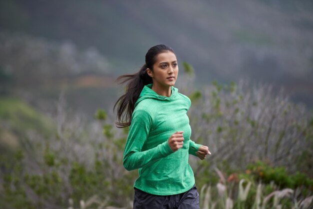 Тренировка в горах Снимок красивой молодой женщины, тренирующейся в горах