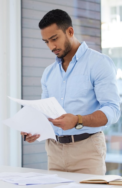 Getting his paperwork in order Shot of a young businessman going through paperwork in an office