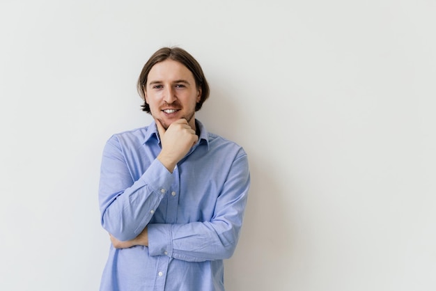 Foto ottenere idea uomo bello premuroso sorridente in piedi su sfondo bianco isolato e toccando il mento con la mano