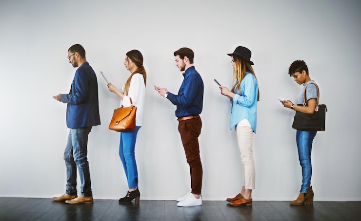 Photo getting last minute tips online before the interview shot of a group of businesspeople using wireless technology while waiting in line