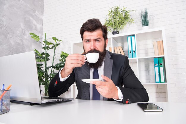 Getting most energy from cup of coffee. Boss drink coffee in office. Bearded man enjoy hot cup. Enjoying hot energy drink. Breakfast tea. Increasing energy levels to work. Wake up and energy with it.
