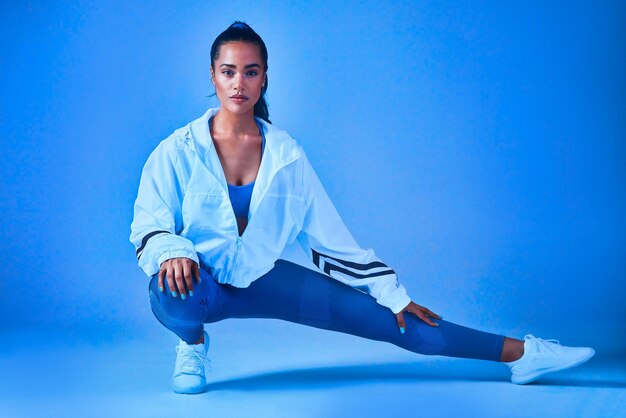 Getting my stretch on Full length portrait of an attractive young female athlete stretching before a workout against a blue background