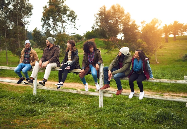 写真 週末に街を出る幸せな友達のグループが一緒に柵の上に並んで座っているショット