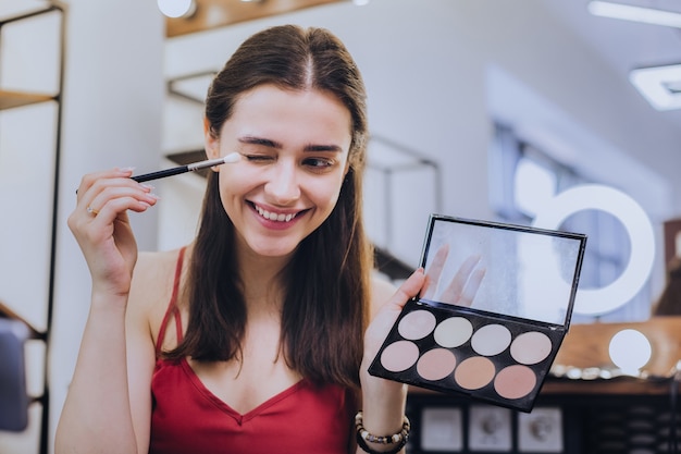 Getting ready. Beaming good-looking woman holding eye brush while getting ready for romantic date