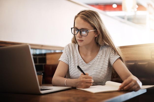 決勝戦の準備カフェのテーブルで勉強するためにラップトップを使用して集中している若い学生のトリミングされたショット