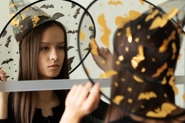 Фото Готовясь к хэллоуину подростка в зеркале в костюме ведьмы перед праздничной вечеринкой