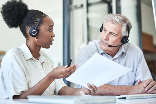 Photo getting some expert advice. shot of two call centre agents sitting together in the office and having a discussion.