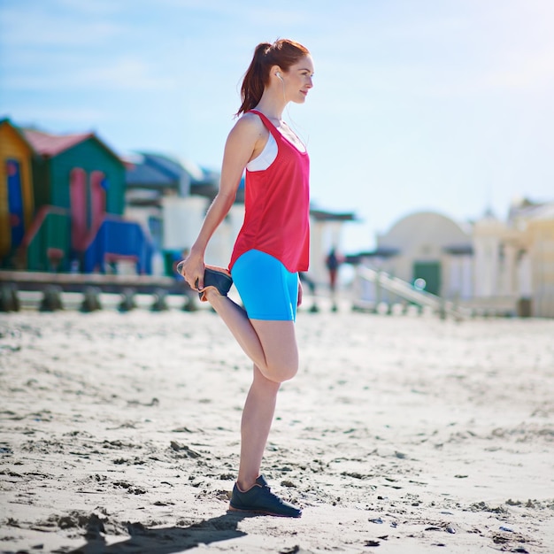 Getting those muscles ready for a workout Full length shot of a young woman stretching before a work out on the beach