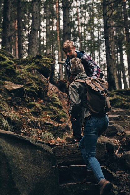 自然と触れ合う。森の中で一緒にハイキングしながら手をつないで上に移動する若いカップル