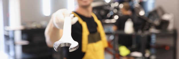 Geüniformeerde autoreparateur houdt moersleutel in autoreparatiewerkplaats autoserviceconcept