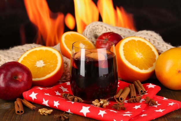 Geurige glühwein in glas op servet op brandachtergrond