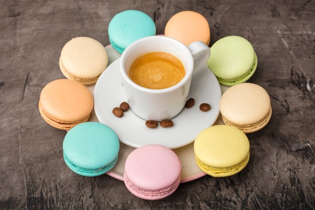 Geurige koffie en kleurrijke macaronkoekjes worden in een cirkel op een bord gerangschikt