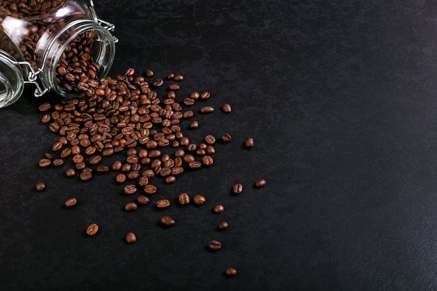 Geurige koffiebonen zijn verspreid uit een pot op een rustieke tafelbladachtergrond