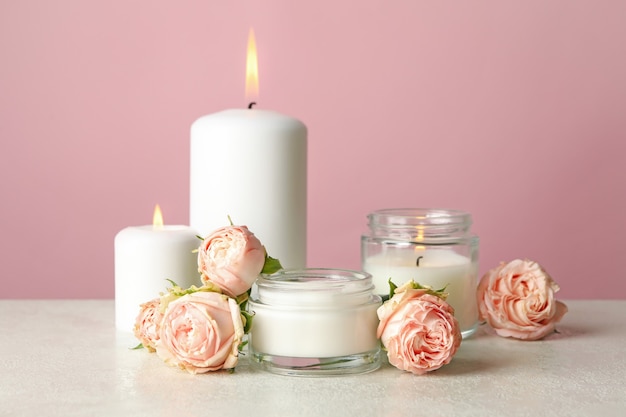 Geurkaarsen en rozen op witte tafel tegen roze oppervlak