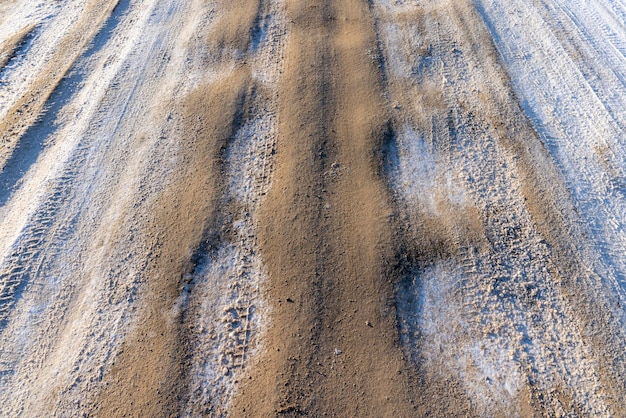 gevaarlijke weg in de winter, gladde modderige weg met sporen van auto's in de winter na sneeuwval,