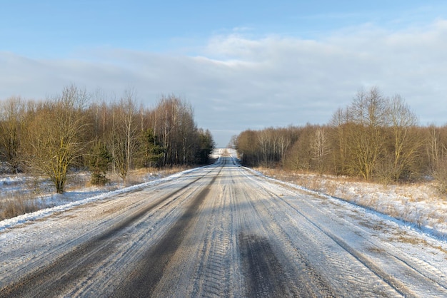 Gevaarlijke weg in de winter gladde modderige weg met sporen van auto's in de winter na sneeuwval